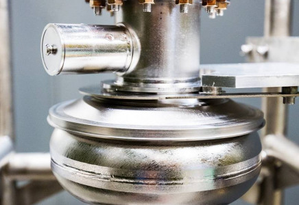 A closeup view of a the silver colored LCLS-II SRF cavity