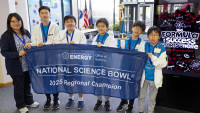 Cooper Middle School Team 1 coach and students holding a "2025 Regional Champion" banner at the Virginia Regional Science Bowl, with a poster stating "The Formula for Success Starts Here" in the background.