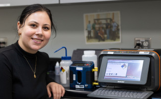 Alicia Haley stands next to a label maker and air monitoring machine