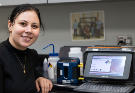 Alicia Haley stands next to a label maker and air monitoring machine