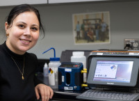 Alicia Haley stands next to a label maker and air monitoring machine