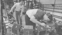 A black-and-white newspaper photo from 1991 shows Nick Sereno checking magnets on small version of the Continuous Electron Beam Accelerator Facility's racetrack-shaped beamline