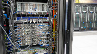 Blue and yellow cables feed into a computing cluster with other servers in the background within the data center at Jefferson Lab.
