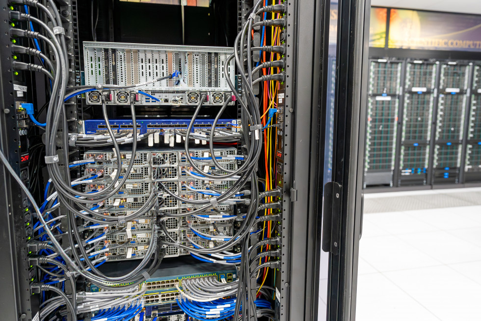 Blue, gray and yellow cables feed into a computing cluster with other servers in the background within the data center at Jefferson Lab.